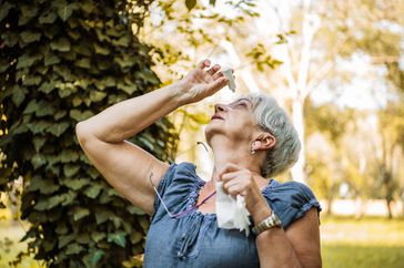 Woman putting eye drops in her eyes