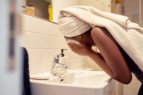 Person washing their face in the sink.
