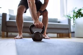 man grabbing kettlebell during home workout barefoot