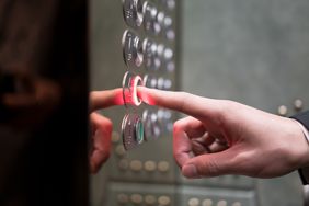 Person pressing elevator button to go to a higher floor