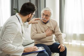 doctor telling older man who is holding his heart about a heart failure diagnosis in a home setting