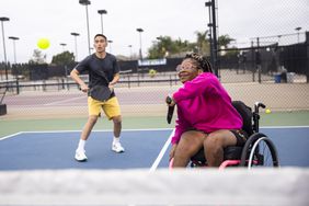 Two people playing doubles tennis outside