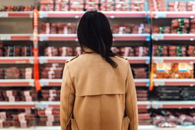 Rear view of woman standing in front of the meat product aisle and struggling which product to choose from. 