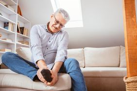 A man holds the bottom of his foot in pain