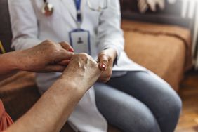 Doctor examining person's fingernails.