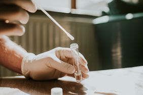 hand wearing gloves collecting covid sample