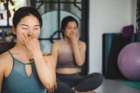 Two people practicing breathing exercises in a yoga class 