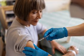 Healthcare professional hands giving vaccine injection in a woman's shoulder. 