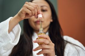 A woman takes out a dropper of peppermint oil