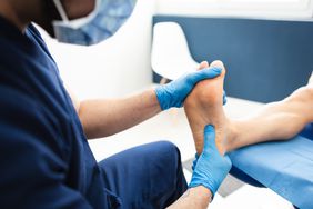 A doctor looks at the bottom of a person's foot