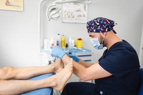 podiatrist checking someone's toenails and feet in a doctor's office