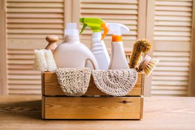basket of cleaning supplies and spray bottles containing denatured alcohol sitting atop a counter