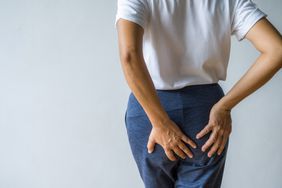 A person holds their hands to their buttocks