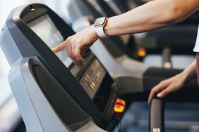 person pressing treadmill buttons