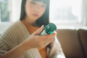 woman looking at supplement bottle