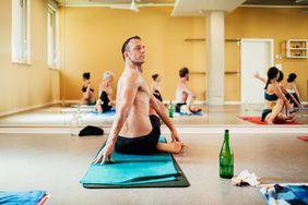 man sitting on towel in hot yoga class