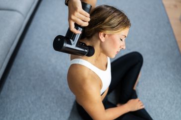 Women using a massage gun on her neck.