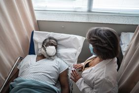 Surgeon talking to a patient in a hospital bed post-surgery.