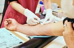 A healthcare worker draws blood from a person's arm