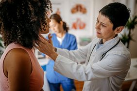 Doctor examines patient's neck in doctor's office.