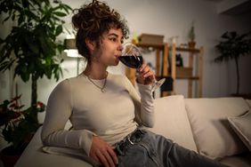 woman drinking glass of wine on sofa