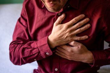 man with esophageal spasm holding his chest