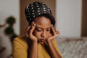 Person holds their temples in pain with a headache.