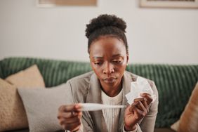 Person taking their temperature with a thermometer at home.