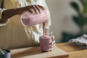 woman pouring smoothie into glass