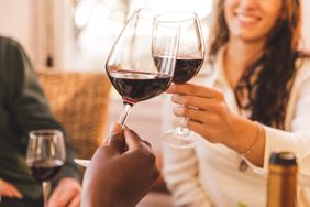 Close up shot of smiling young woman making a celebratory toast with red wine.