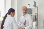 Woman doctor cardiologist listens with stethoscope to patient senor man in clinic office. Visit to the doctor in a medical hospital