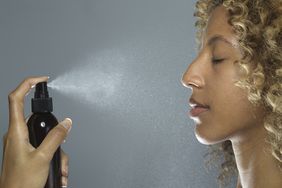 Profile of a woman spraying facial mist on her face. 