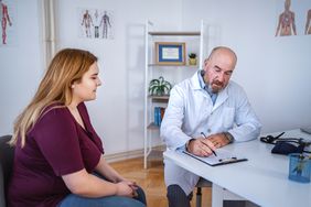 Young female patient talking with an experienced doctor at the doctor's office.
