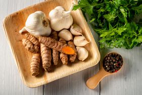 Wooden plate with garlic bulbs, cloves, and turmeric root