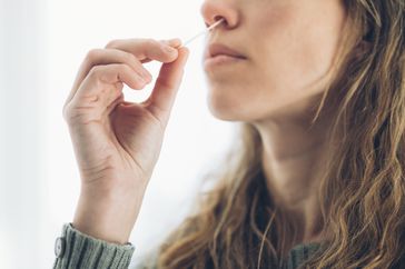 Woman inserting a swab into nostil.