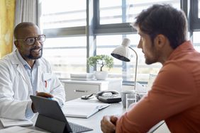 Young white male patient discussing health results with a black male doctor, in a doctor office setting