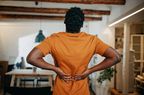 Person holds their lower back in pain.
