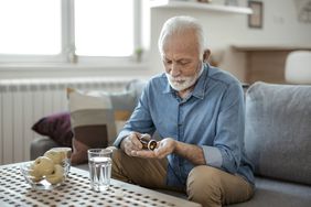 senior male taking pills on sofa