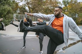 A man does a high kick to warm up before exercising