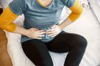 A woman holds her hands to her stomach