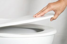 man's hand opening the toilet lid