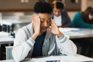 A young man tries to concentrate on his schoolwork 