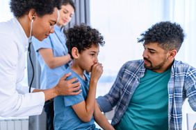 A doctor listens to a child's lungs as the child coughs