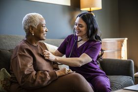 A nurse listens to a woman's heart with a stethoscope