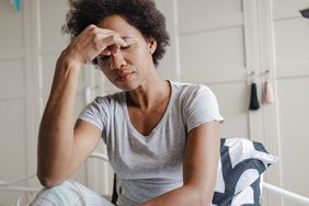 Woman seems distressed, is holding her head at her nose's bridge.