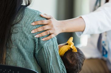 mental health provider puts arm around woman experiencing postpartum depression