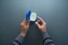 Top view of man hand using petroleum jelly on black background