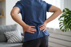 Back pain, kidney inflammation, man suffering from backache at home