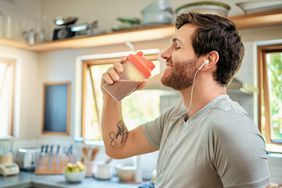 Young white man drinking a protein shake in a kitchen