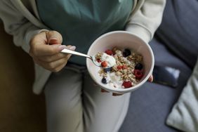 Person holding bowl of yogurt and muesli